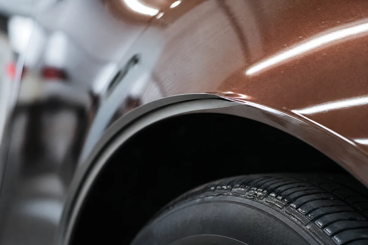 Détail d&rsquo;un bord de film qui se décolle légèrement au niveau d&rsquo;un passage de roue de voiture